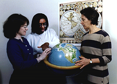 [Photo of Cathy Soussloff, Margo Hendricks, and Karen Bassi around a world globe]
