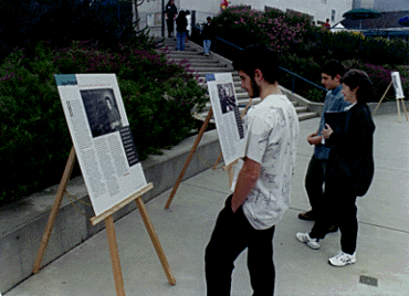 [Photo of people looking at Scholars Day Review magazine display]