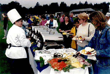 [Picture of Chancellor Greenwood serving staff at staff barbecue]